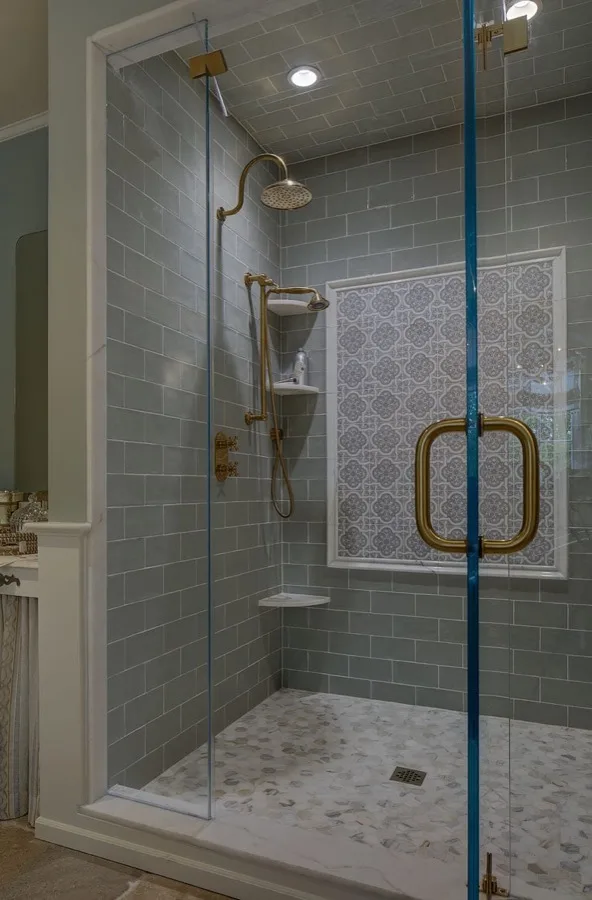 French Country inspired master bathroom shower with gold fixtures and patterned tile